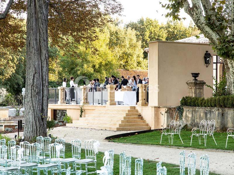 Groupe de personnes réunies sur une terrasse surélevée, entourée de verdure et de mobilier de jardin.
