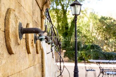 Chambre lumineuse avec murs orange, lit double, sol en terre cuite, table près d'une fenêtre et cloison en bois.