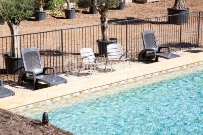 Chambre lumineuse avec murs orange, lit double, sol en terre cuite, table près d'une fenêtre et cloison en bois.