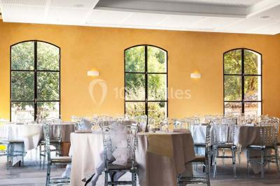 Chambre lumineuse avec murs orange, lit double, sol en terre cuite, table près d'une fenêtre et cloison en bois.