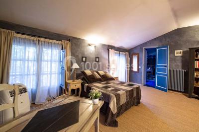 Chambre lumineuse avec murs orange, lit double, sol en terre cuite, table près d'une fenêtre et cloison en bois.