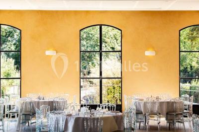 Chambre lumineuse avec murs orange, lit double, sol en terre cuite, table près d'une fenêtre et cloison en bois.