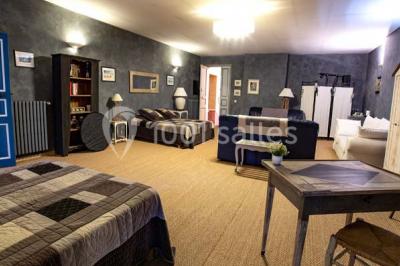 Chambre lumineuse avec murs orange, lit double, sol en terre cuite, table près d'une fenêtre et cloison en bois.