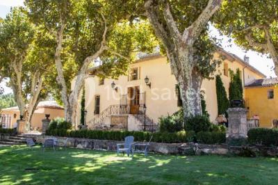 Chambre lumineuse avec murs orange, lit double, sol en terre cuite, table près d'une fenêtre et cloison en bois.