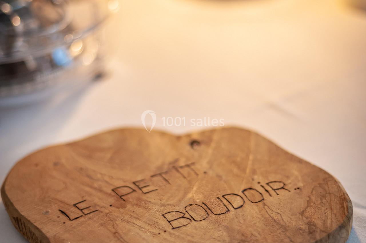 Planche en bois gravée ’Le Petit Boudoir’ posée sur une table éclairée par une lumière douce.