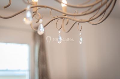 Maison entourée de verdure avec un chemin en gravier, des arbres et une terrasse visible en arrière-plan.
