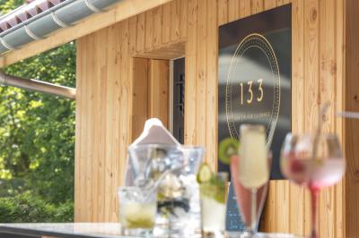 Maison entourée de verdure avec un chemin en gravier, des arbres et une terrasse visible en arrière-plan.