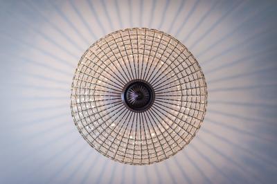 Maison entourée de verdure avec un chemin en gravier, des arbres et une terrasse visible en arrière-plan.