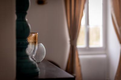 Maison entourée de verdure avec un chemin en gravier, des arbres et une terrasse visible en arrière-plan.