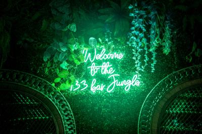 Maison entourée de verdure avec un chemin en gravier, des arbres et une terrasse visible en arrière-plan.