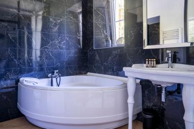 Maison entourée de verdure avec un chemin en gravier, des arbres et une terrasse visible en arrière-plan.