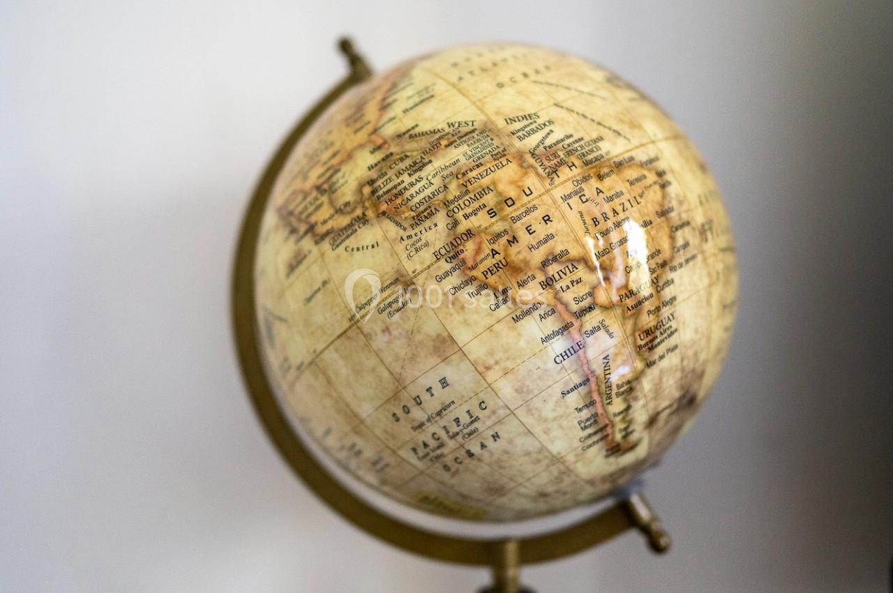 Globe terrestre vintage posé sur une table en marbre, montrant une carte ancienne des continents.