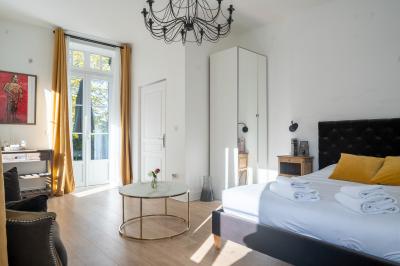 Maison entourée de verdure avec un chemin en gravier, des arbres et une terrasse visible en arrière-plan.