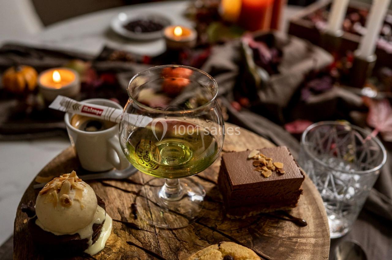 Dessert sur une planche en bois avec glace, muffin, gâteau au chocolat, verre de liqueur et bougies en arrière-plan.