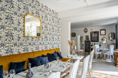 Maison entourée de verdure avec un chemin en gravier, des arbres et une terrasse visible en arrière-plan.