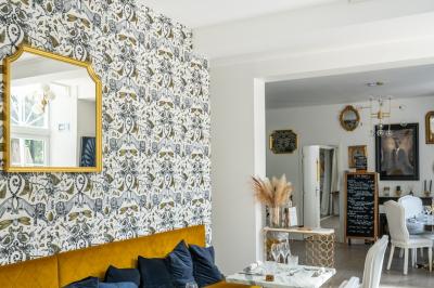 Maison entourée de verdure avec un chemin en gravier, des arbres et une terrasse visible en arrière-plan.