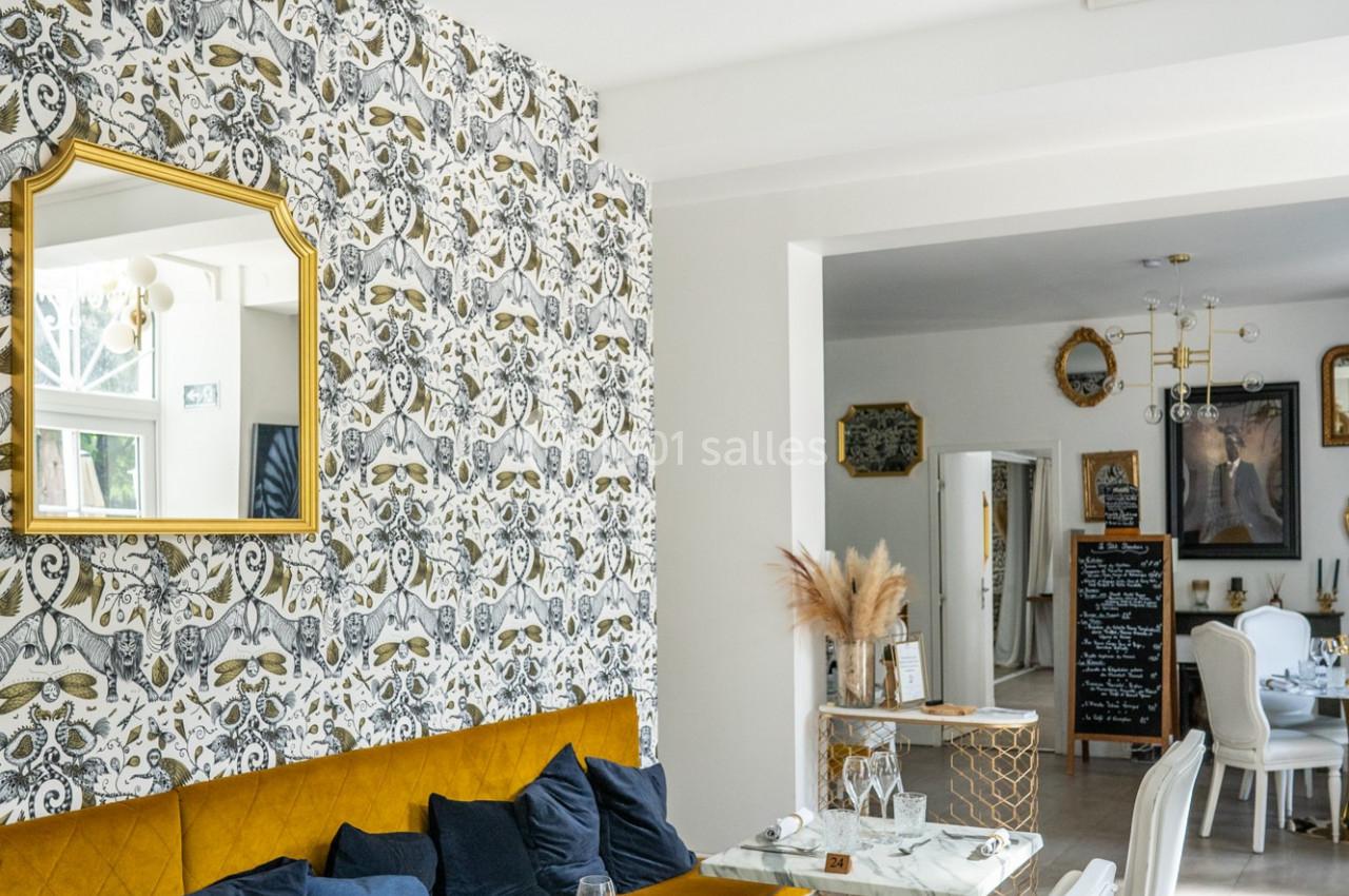 Salle à manger lumineuse avec tables en marbre, chaises blanches, banquette jaune et décoration murale élégante.