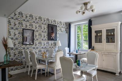 Maison entourée de verdure avec un chemin en gravier, des arbres et une terrasse visible en arrière-plan.