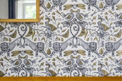 Maison entourée de verdure avec un chemin en gravier, des arbres et une terrasse visible en arrière-plan.