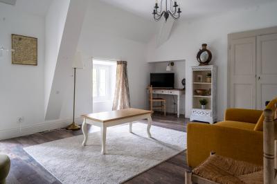 Maison entourée de verdure avec un chemin en gravier, des arbres et une terrasse visible en arrière-plan.
