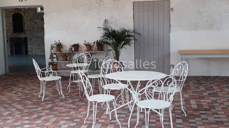 Mobilier de jardin en fer forgé blanc disposé sur un sol en carreaux colorés, avec des plantes en arrière-plan.