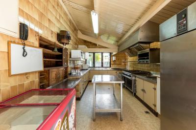 Un jardin verdoyant avec pelouse, arbres, arbustes et une charrette ancienne près d'un abri en bois.