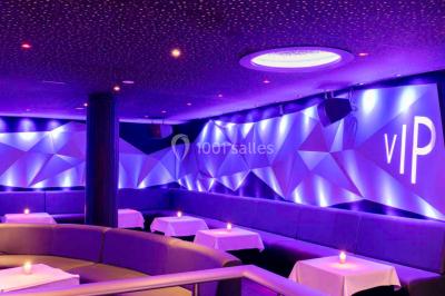 Entrée d'un espace moderne avec éclairage bleu, tapis rouge et panneau lumineux affichant un logo.