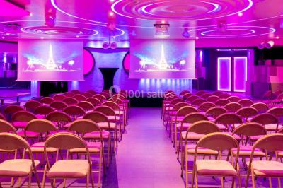 Entrée d'un espace moderne avec éclairage bleu, tapis rouge et panneau lumineux affichant un logo.