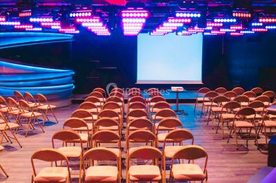 Entrée d'un espace moderne avec éclairage bleu, tapis rouge et panneau lumineux affichant un logo.
