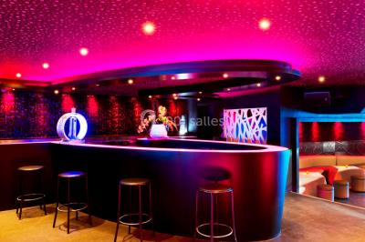 Entrée d'un espace moderne avec éclairage bleu, tapis rouge et panneau lumineux affichant un logo.