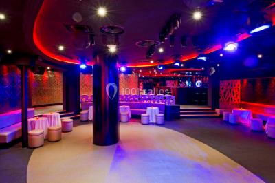 Entrée d'un espace moderne avec éclairage bleu, tapis rouge et panneau lumineux affichant un logo.