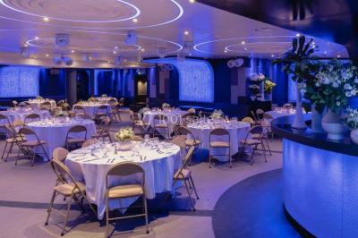 Entrée d'un espace moderne avec éclairage bleu, tapis rouge et panneau lumineux affichant un logo.