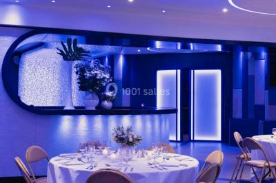 Entrée d'un espace moderne avec éclairage bleu, tapis rouge et panneau lumineux affichant un logo.