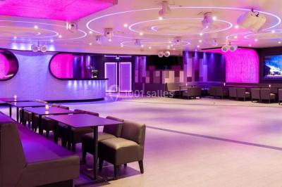 Entrée d'un espace moderne avec éclairage bleu, tapis rouge et panneau lumineux affichant un logo.