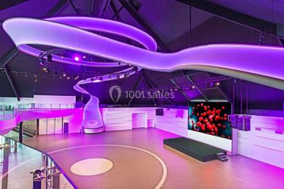 Tables rondes dressées avec nappes bleues alignées sur une pelouse, entourées d'arbres, avec un parc en arrière-plan.