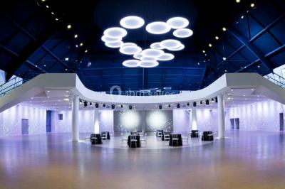 Tables rondes dressées avec nappes bleues alignées sur une pelouse, entourées d'arbres, avec un parc en arrière-plan.