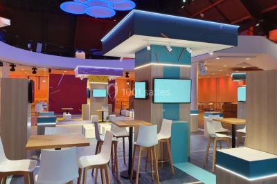 Tables rondes dressées avec nappes bleues alignées sur une pelouse, entourées d'arbres, avec un parc en arrière-plan.