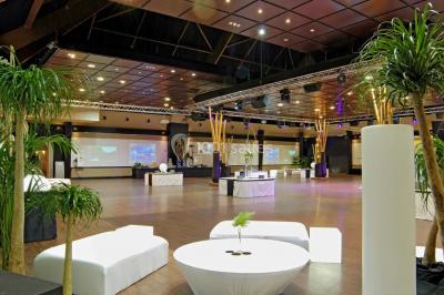 Tables rondes dressées avec nappes bleues alignées sur une pelouse, entourées d'arbres, avec un parc en arrière-plan.