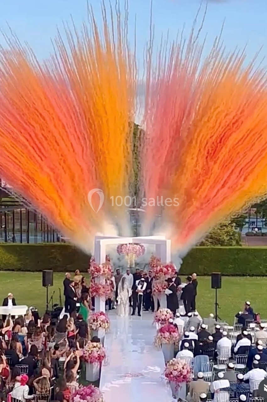 Cérémonie de mariage en plein air avec des jets de fumée colorée orange et jaune en arrière-plan.