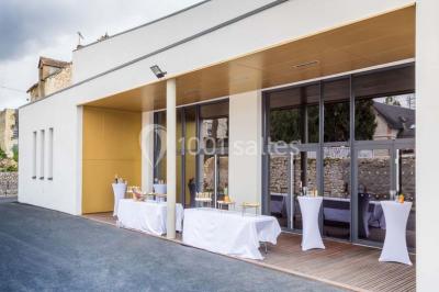 Dessert en forme de cœur au chocolat sur une assiette blanche, accompagné de coulis rouge et d'une verrine en arrière-plan.