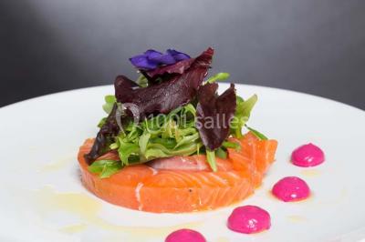 Mousse orange servie dans un verre, décorée d'un physalis et d'un segment de pamplemousse, posée sur une napperon blanc.