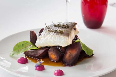 Mousse orange servie dans un verre, décorée d'un physalis et d'un segment de pamplemousse, posée sur une napperon blanc.