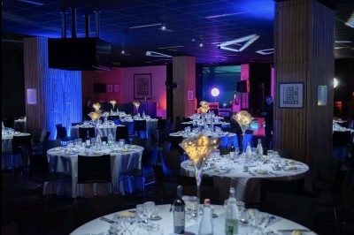 Salle aménagée avec des tables hautes et des comptoirs colorés, éclairée par des lumières chaleureuses.