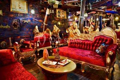 Vue nocturne d'un complexe de loisirs avec piscine illuminée, bâtiments thématiques et paysage urbain en arrière-plan.