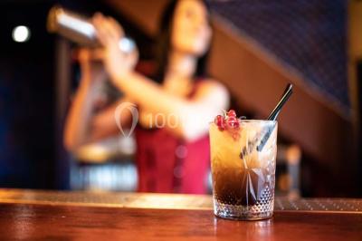 Vue nocturne d'un complexe de loisirs avec piscine illuminée, bâtiments thématiques et paysage urbain en arrière-plan.