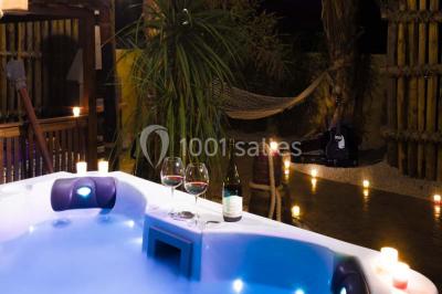 Vue nocturne d'un complexe de loisirs avec piscine illuminée, bâtiments thématiques et paysage urbain en arrière-plan.