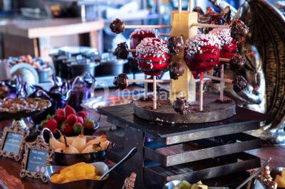 Vue nocturne d'un complexe de loisirs avec piscine illuminée, bâtiments thématiques et paysage urbain en arrière-plan.