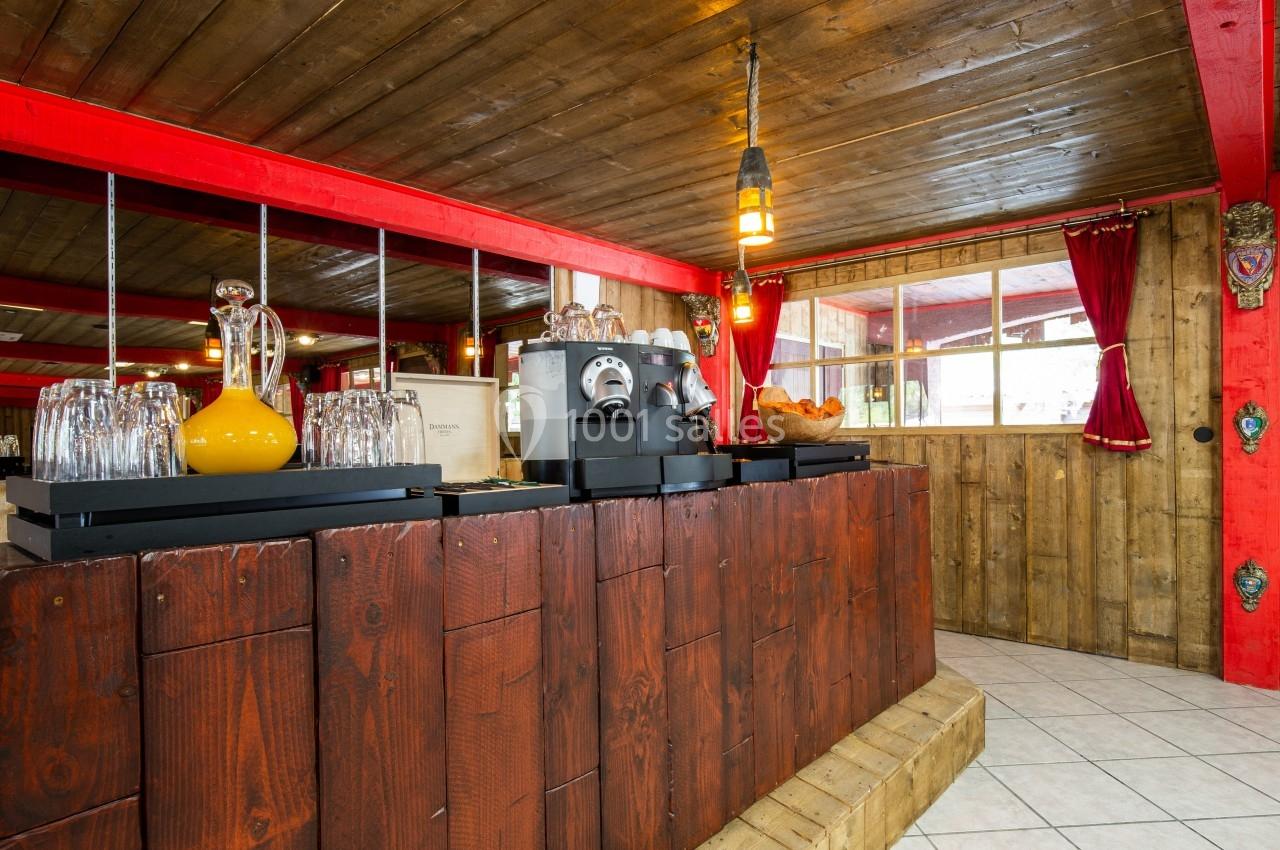 Comptoir en bois avec machine à café, carafe de jus d'orange et panière de pain dans un intérieur rustique éclairé.