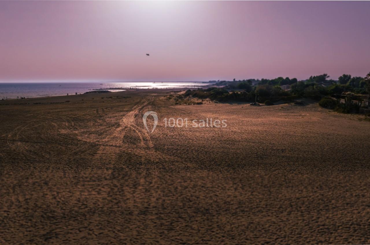 Plage déserte au coucher du soleil avec une lumière douce sur le sable et la mer à l'horizon.