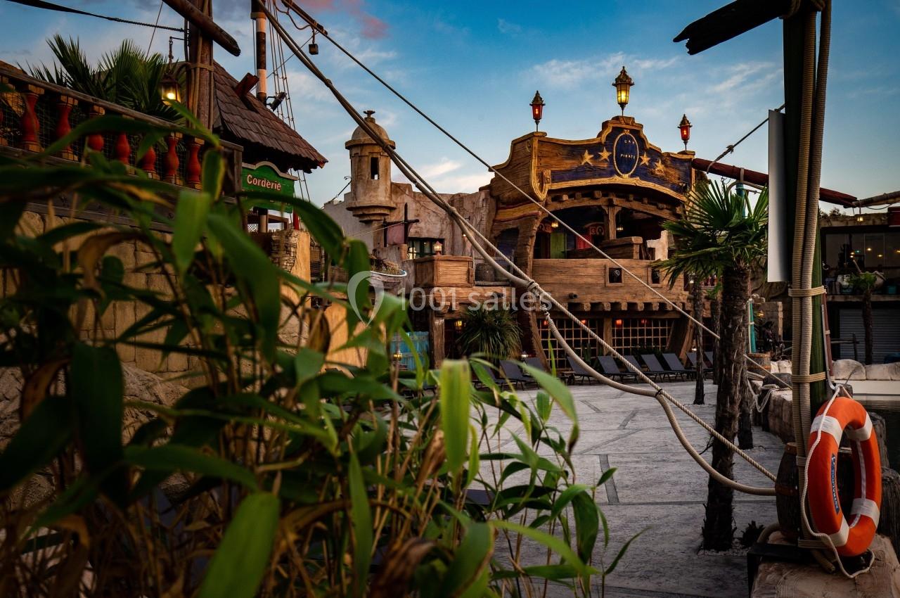 Façade d'un bâtiment à thème pirate avec des décorations en bois, des cordages et des plantes au premier plan.